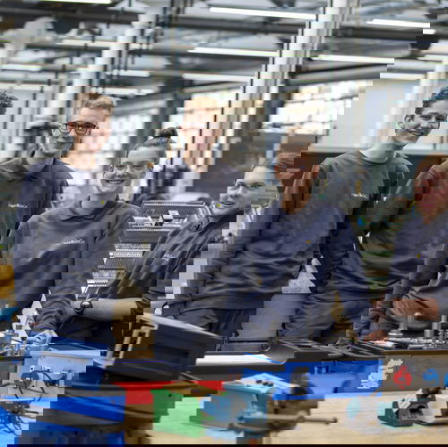 Trainees wearing grey jumpers in workshop