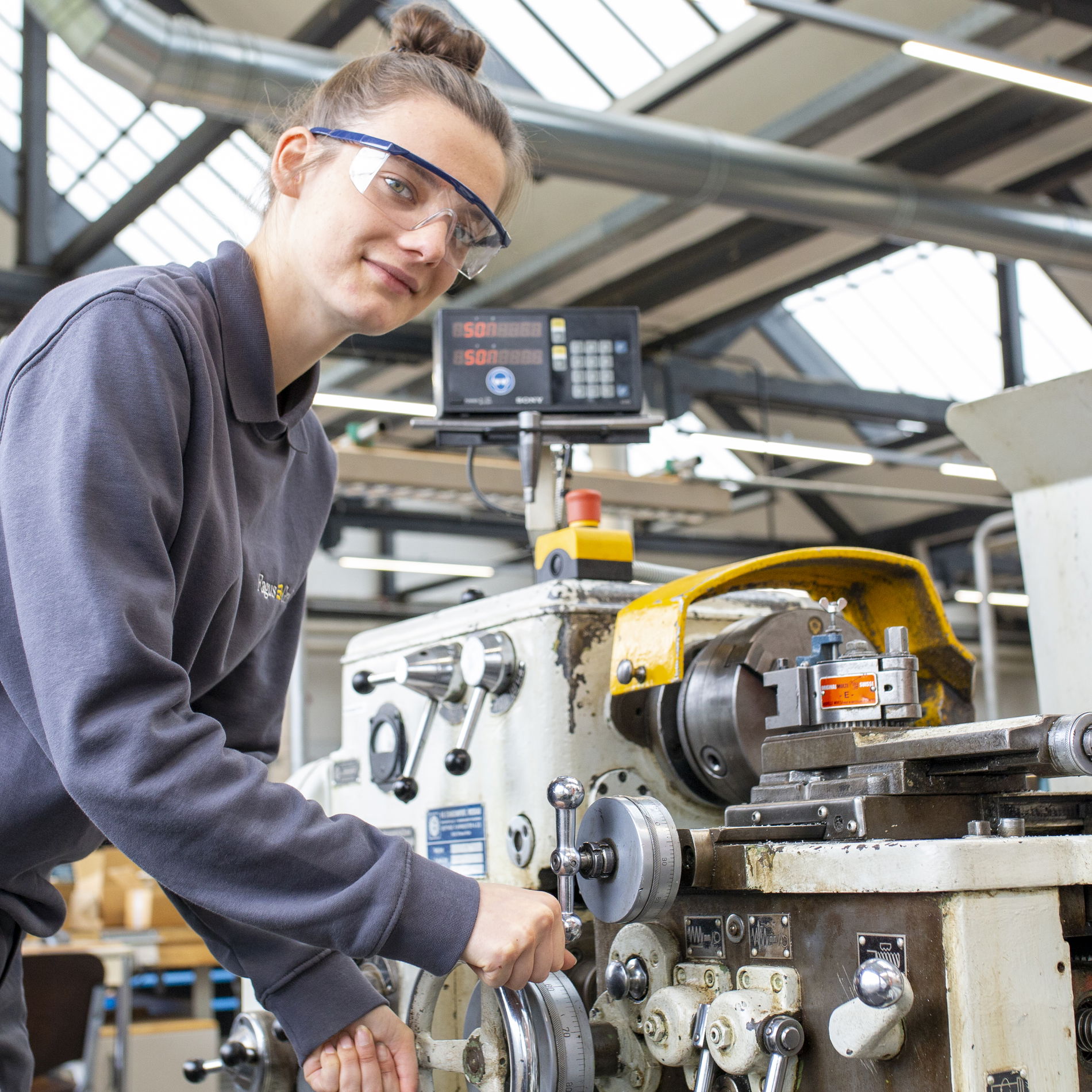 Trainee in grey jumper in front of heavy machine