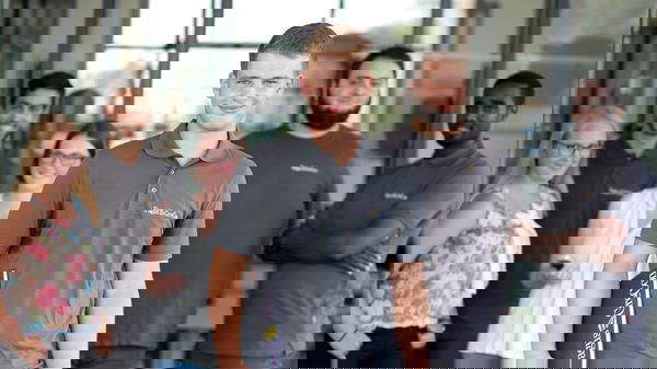 Trainee wearing a grey polo shirt standing in front of other trainees