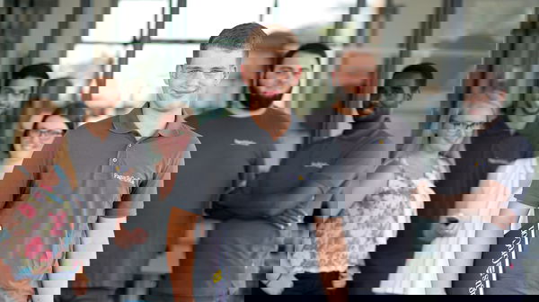 Trainee wearing a grey polo shirt standing in front of other trainees