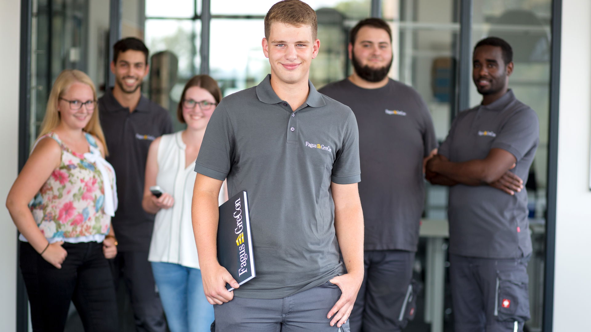 Trainee wearing a grey polo shirt standing in front of other trainees