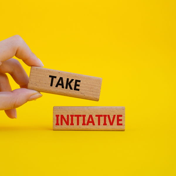 Take initiative written on stones in front of a yellow wall