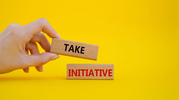 Tome a iniciativa escrita em pedras na frente de uma parede amarela