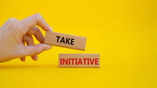 Take initiative written on stones in front of a yellow wall
