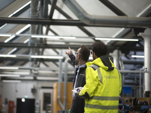 Two people inspecting spark extinguishing system in industrial hall