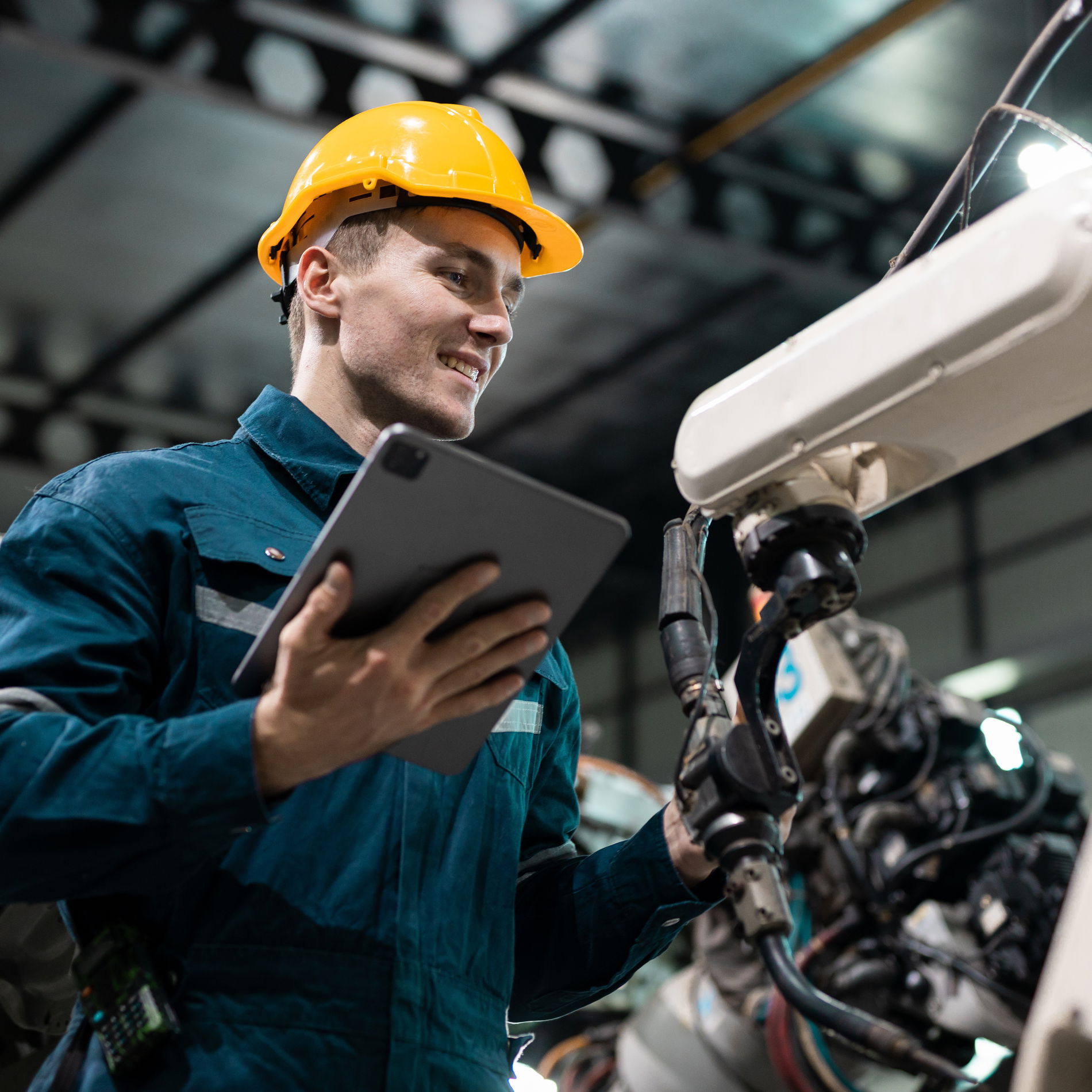 Worker wearing a yellow helmet in front of a hydraulic machine