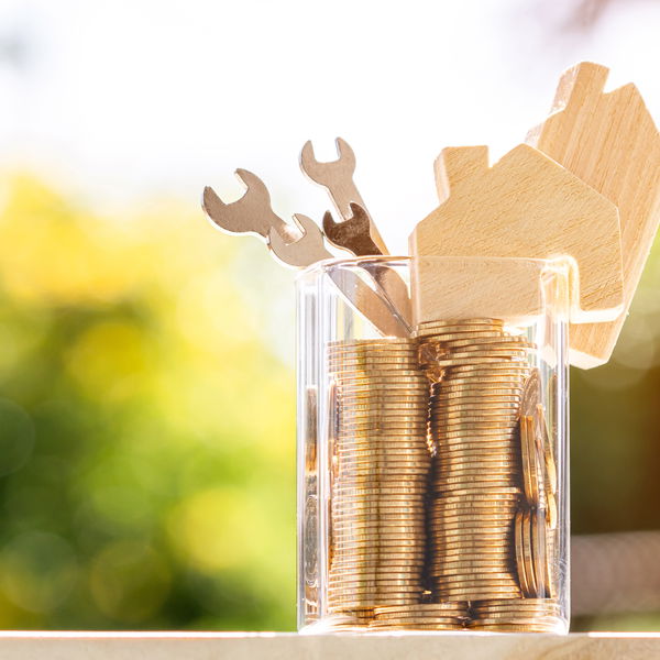 glass jar with coins, wooden screwdriver and toy-sized wooden house