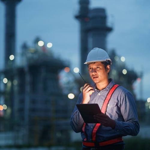 Workers in front of industrial plant with walkie-talkie