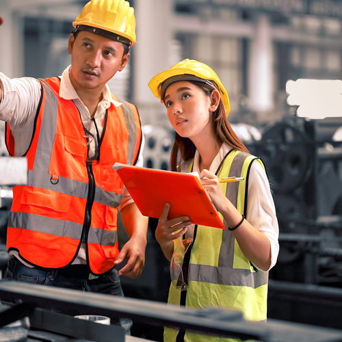 [Translate to Português brasileiro BR:] Workers with yellow helmets looking on machine