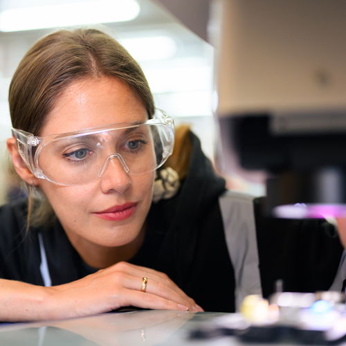 Woman wearing safety goggles looks at light source