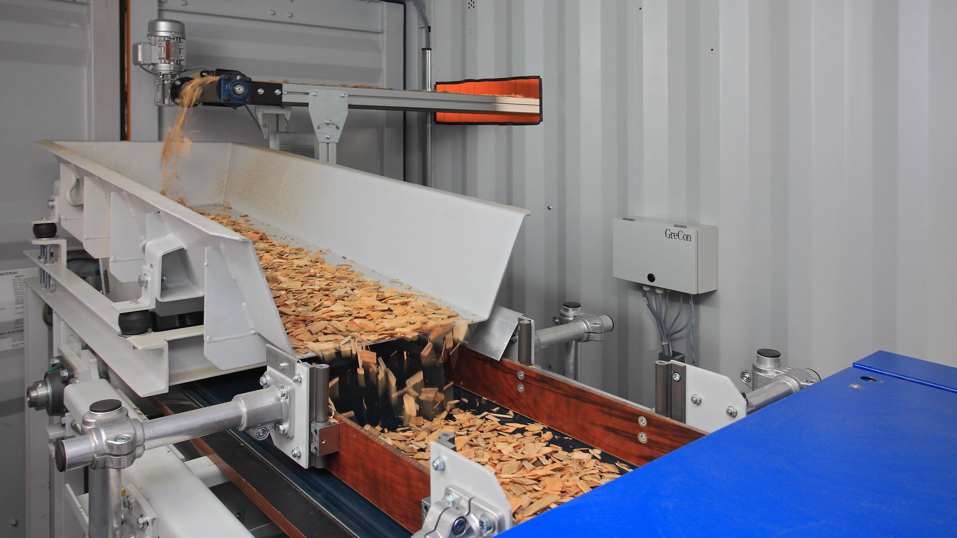 Wood chips running along a conveyor belt in a production facility.