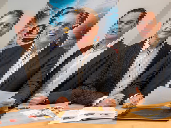 Drei Geschäftsführer von Fagus-GreCon vor Stehtisch.